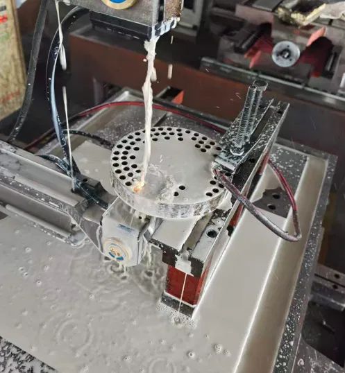 Wire EDM eroder actively cutting with dielectric fluid flushing the cutting zone